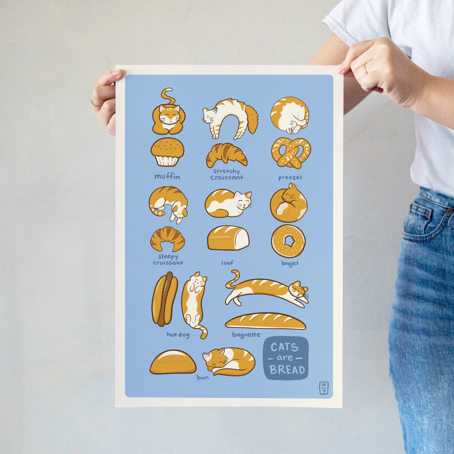 Cats are Bread large print with cute cats in different poses next to breads being held by the corners against a wall
